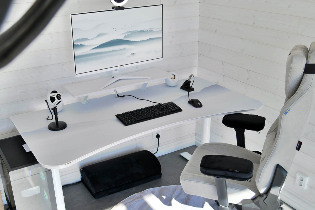 Minimalist white desk setup with monitor, keyboard, mouse, microphones, and gray chair.