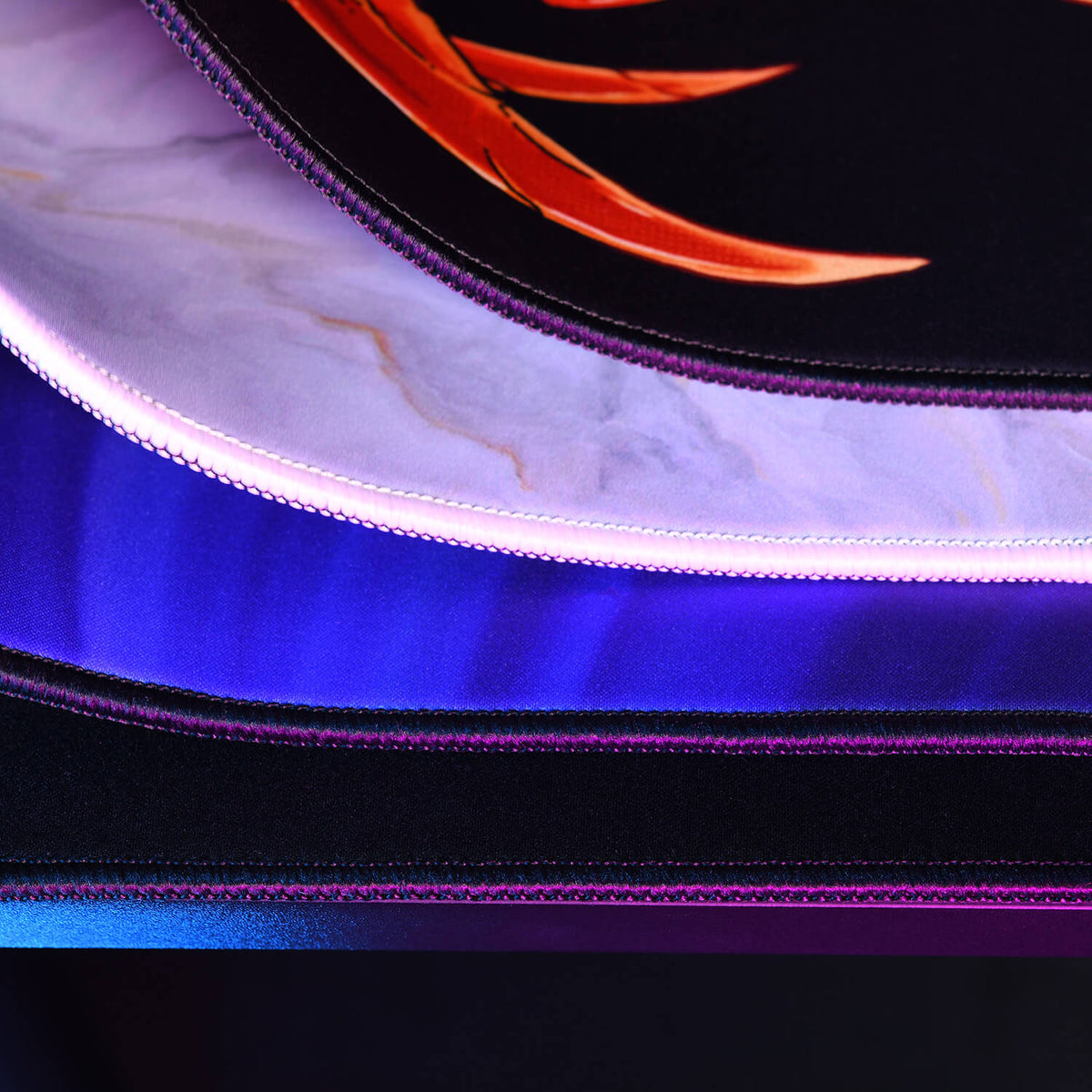Stacked colorful mouse pads with stitched edges and LED lighting, viewed close up.
