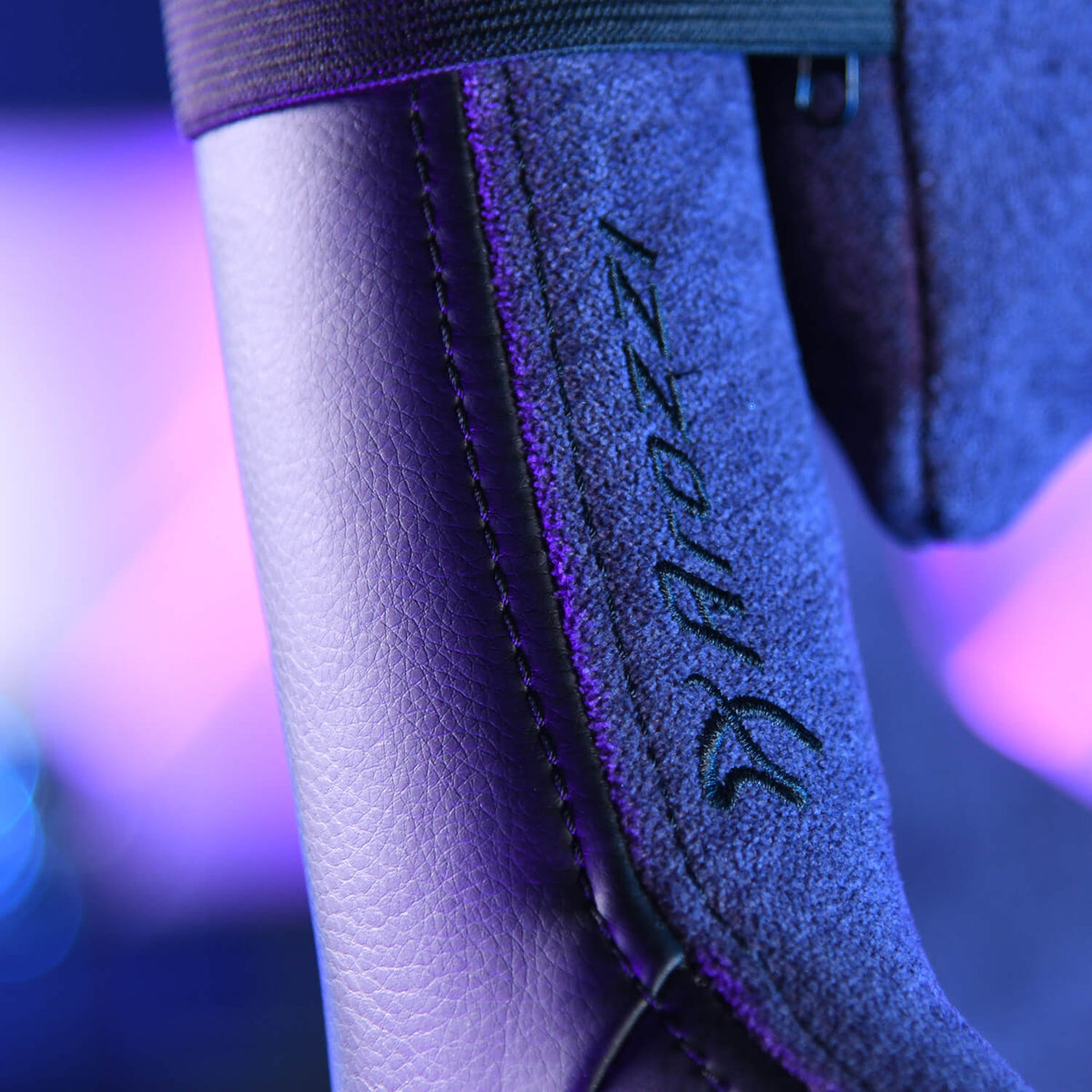 Close-up of a chairs stitched armrest with the word Razer embroidered on suede material.