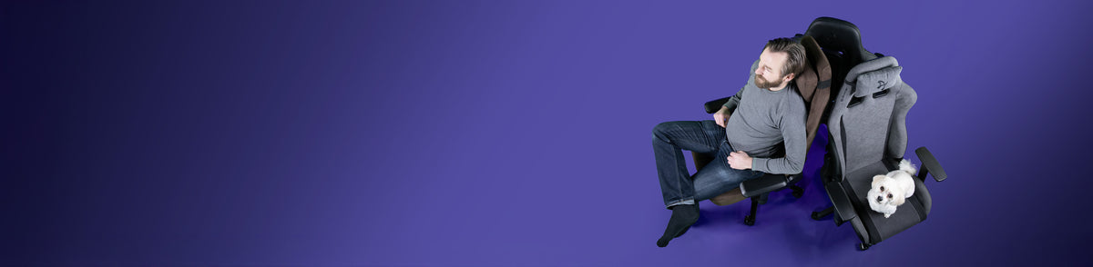 Man sitting on a chair next to a dog on another chair, on a purple background.