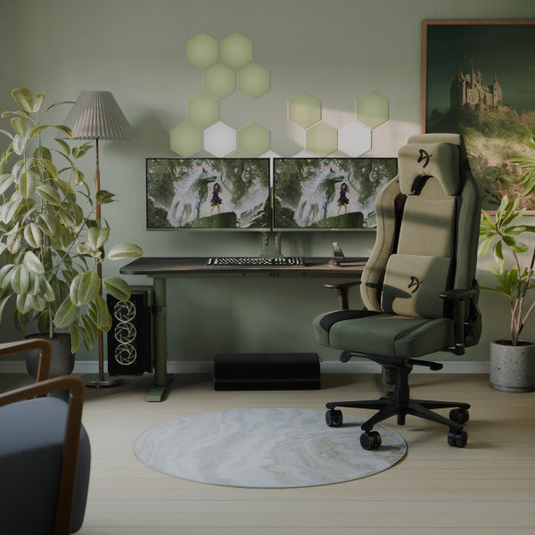 Modern gaming desk with dual monitors, gaming chair, plants, and wall hexagon lights.