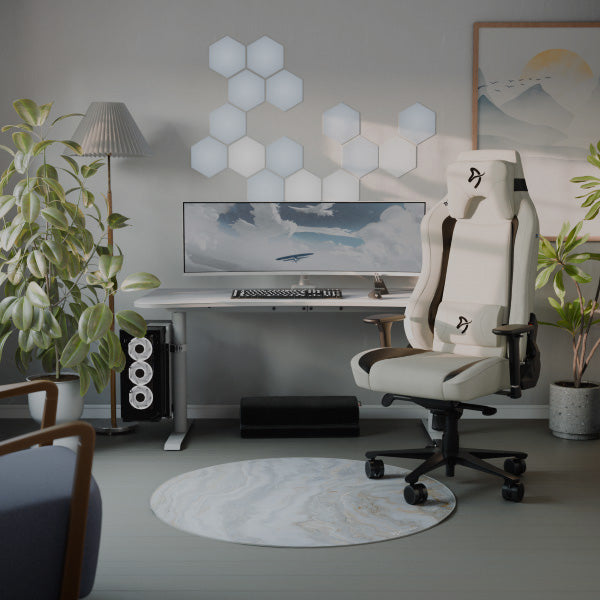 Modern desk setup with a white gaming chair, plants, and wall hexagon lights.