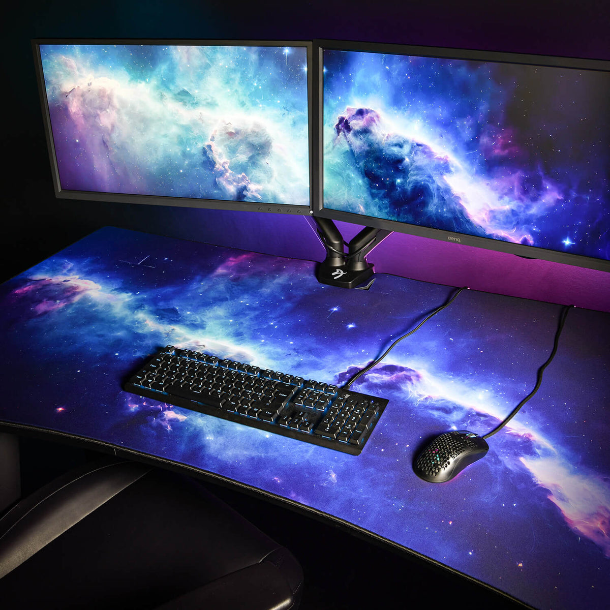 Arozzi Europe Arena Mousepad with dual monitors, keyboard, mouse & galaxy wallpaper on desk.