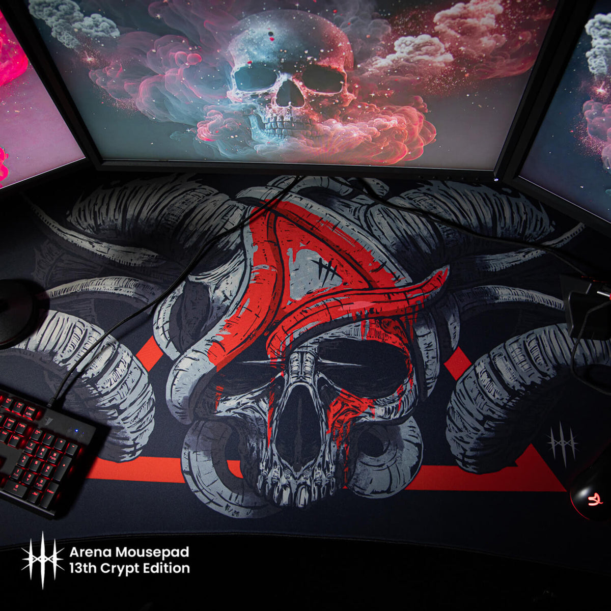Arozzi Europe Arena Mousepad with a horned skull, shown under 3 monitors and beside keyboards.