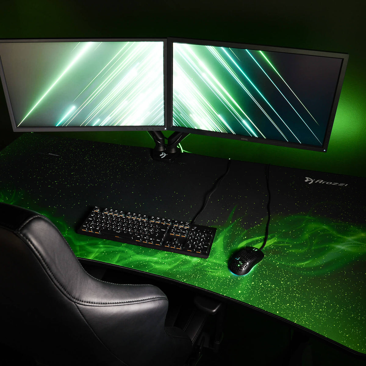 Dual monitors on dark desk with green lighting, keyboard, mouse, and Arozzi Arena Mousepad.