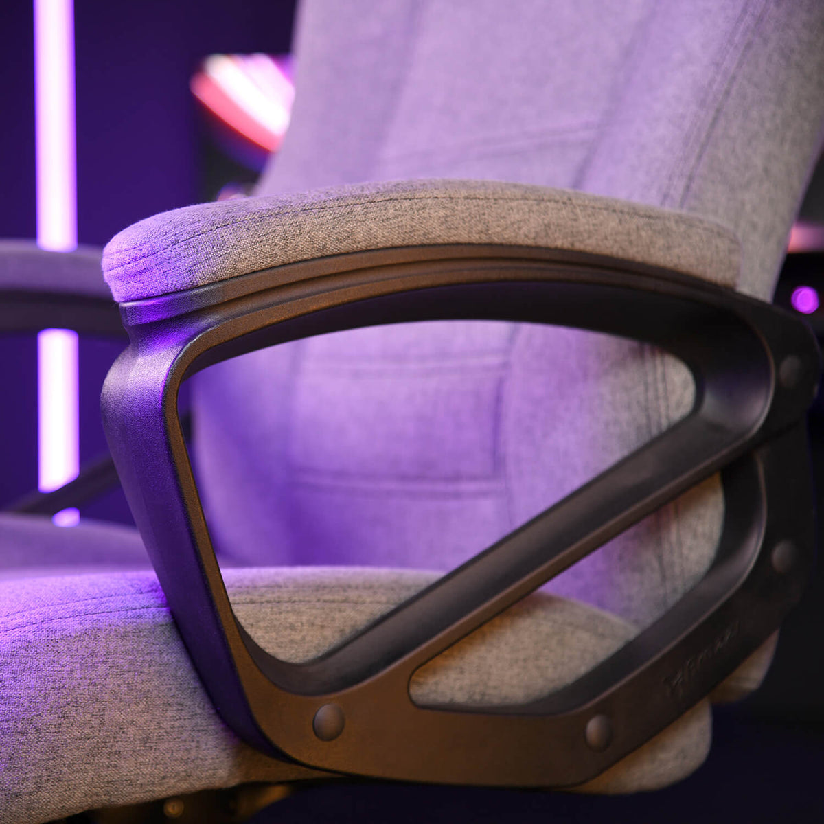 Close-up of a gray fabric chair with a black armrest and purple lighting.