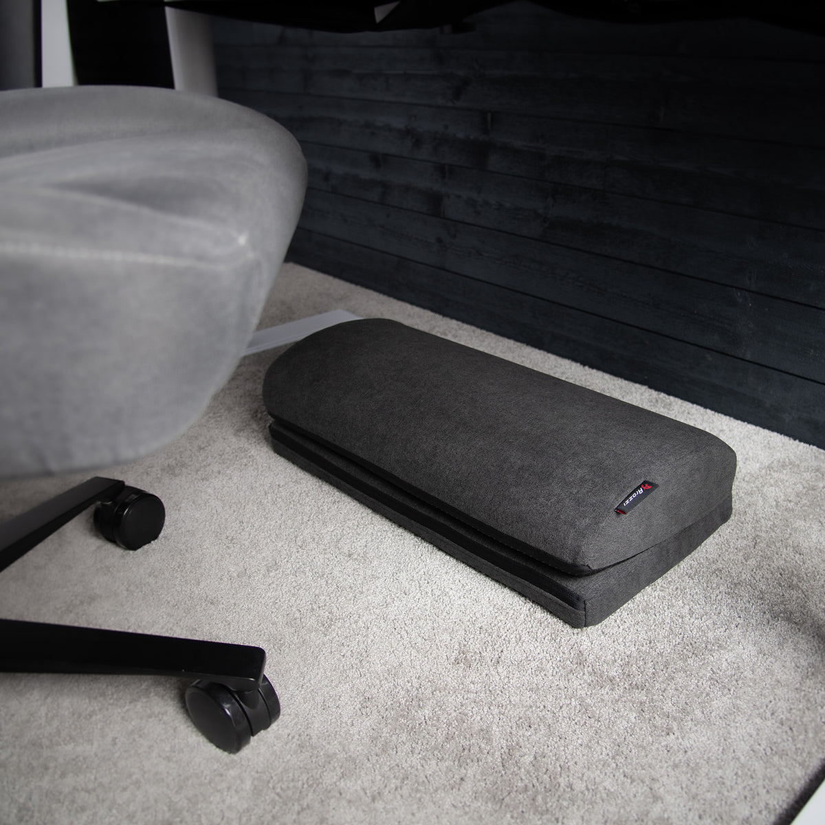 Arozzi Europe Footrest under desk on light carpet, beneath office chair with wheels.