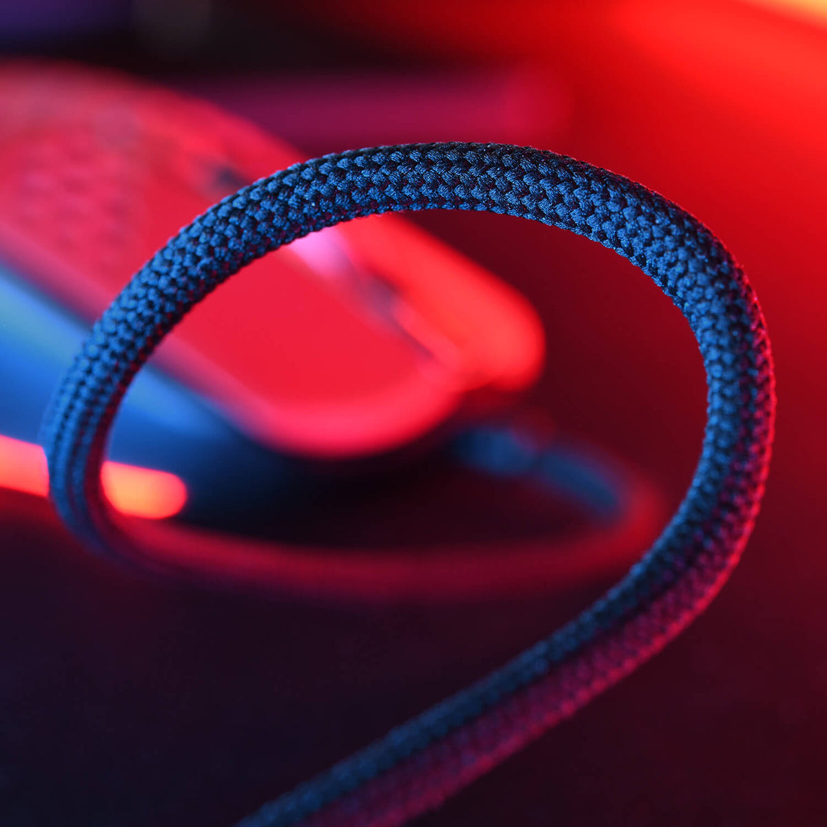 Close-up of a braided mouse cable, with blurred red and blue lighting in the background.