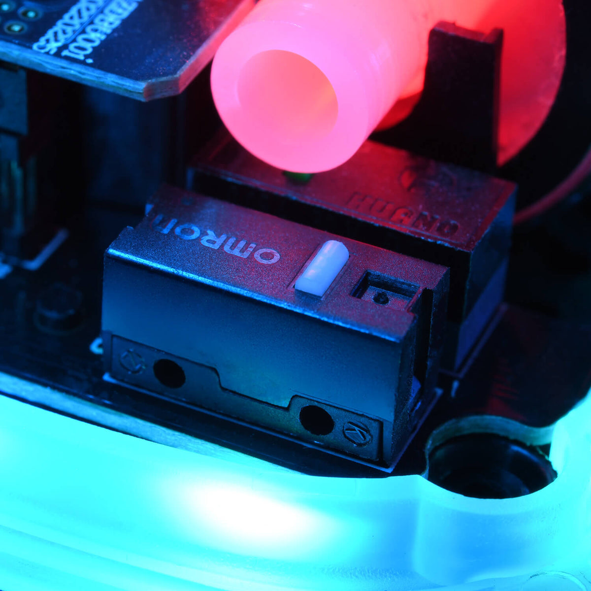 Close-up of an Omron switch with blue and pink lighting on an electronic circuit board.