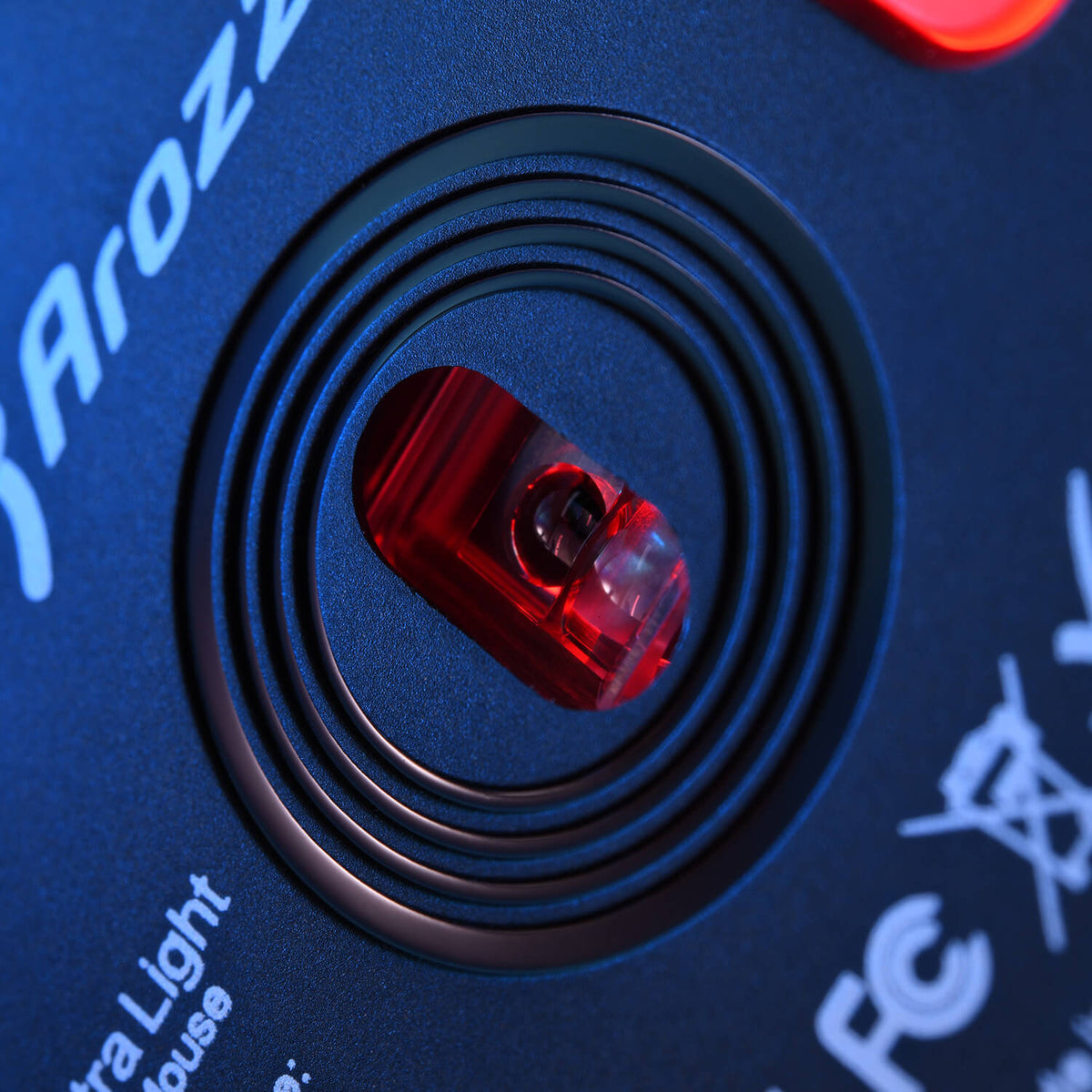 Close-up of a computer mouse sensor with red light and circular design around it.