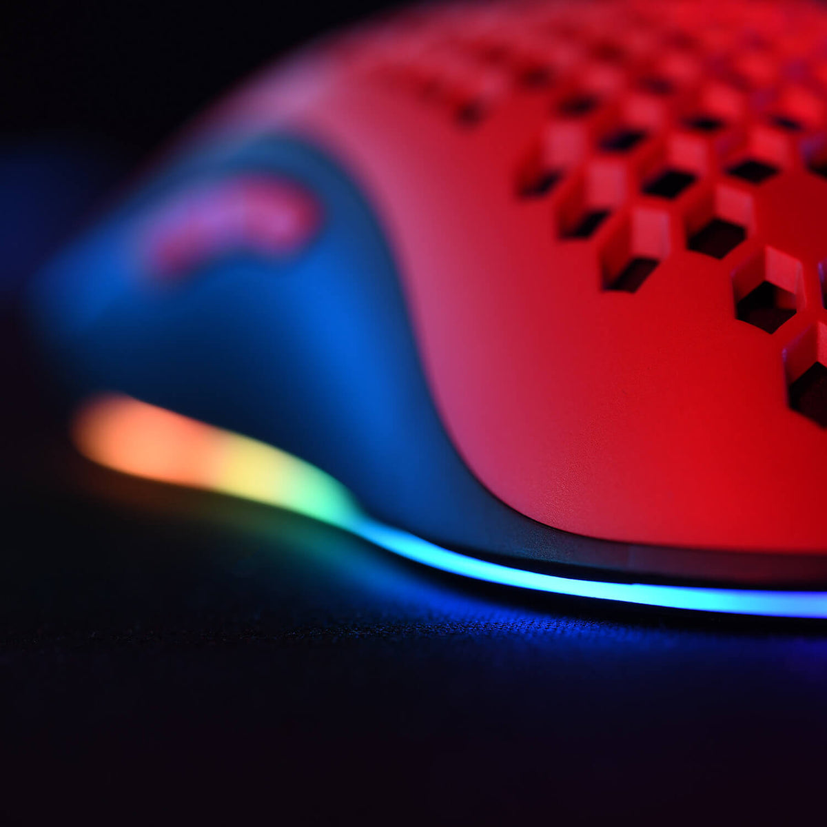 Close-up of a red gaming mouse with RGB lighting along the bottom edge.