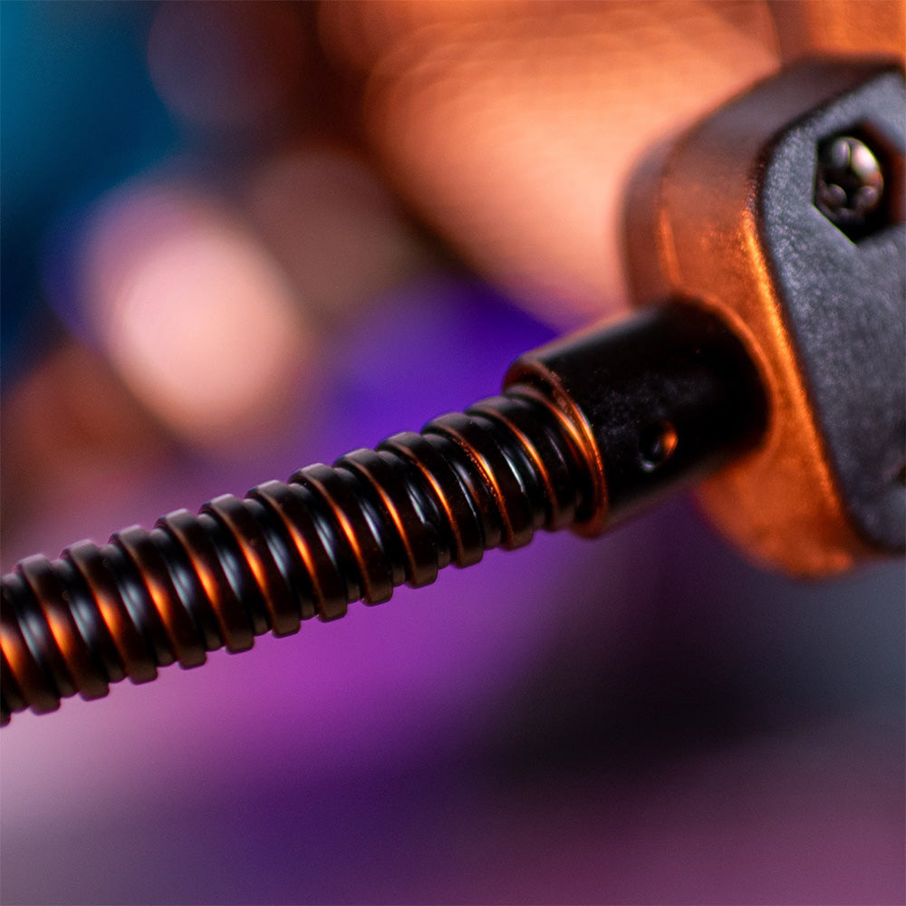 Close-up of a coiled metal spring with a blurred background in purple and orange tones.