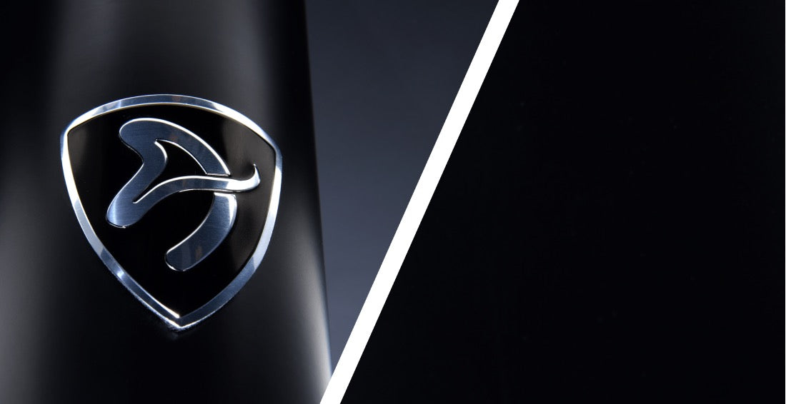 Silver abstract logo on a black surface, divided diagonally by a white line.