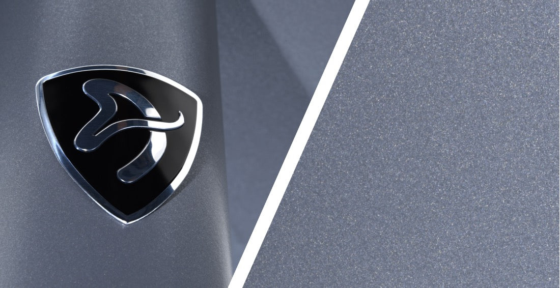 A silver and black logo on a metallic gray background, split by a white diagonal line.