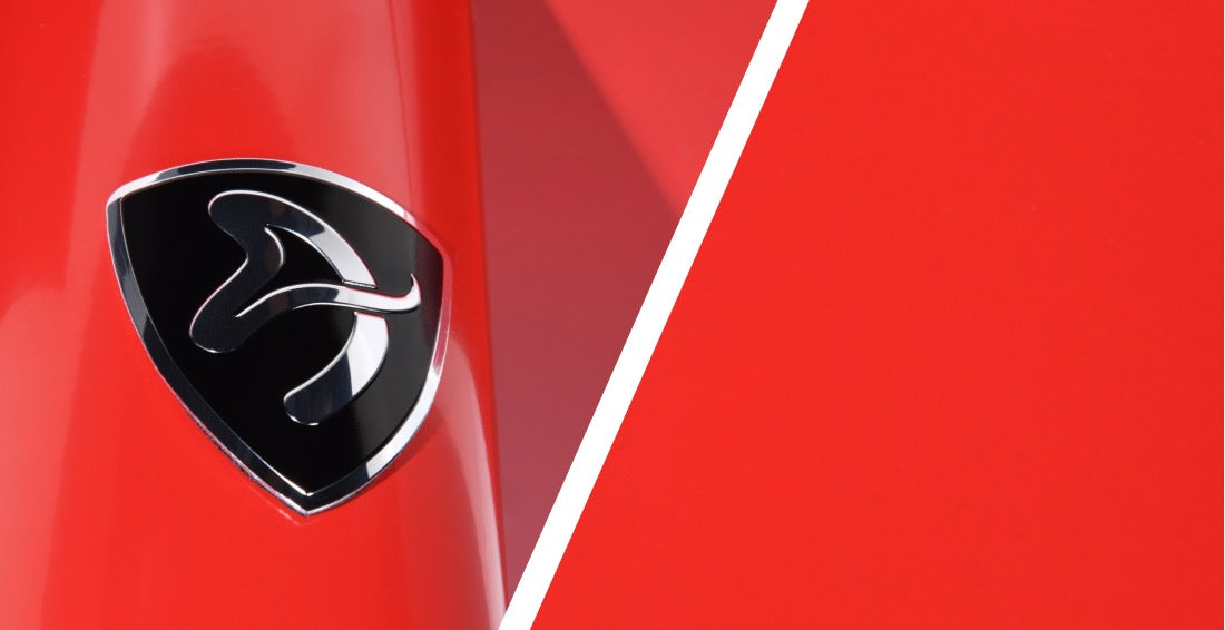 Black and silver shield logo on a shiny red surface divided by a white diagonal line.