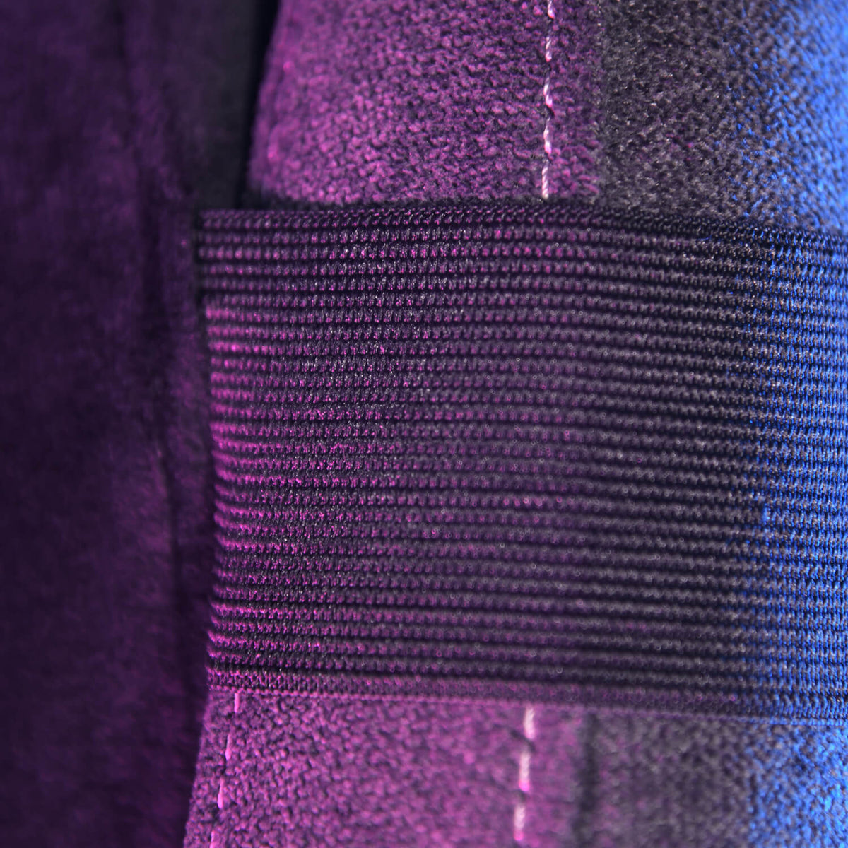 Close-up of a black ribbed strap on a purple fabric with visible stitching.