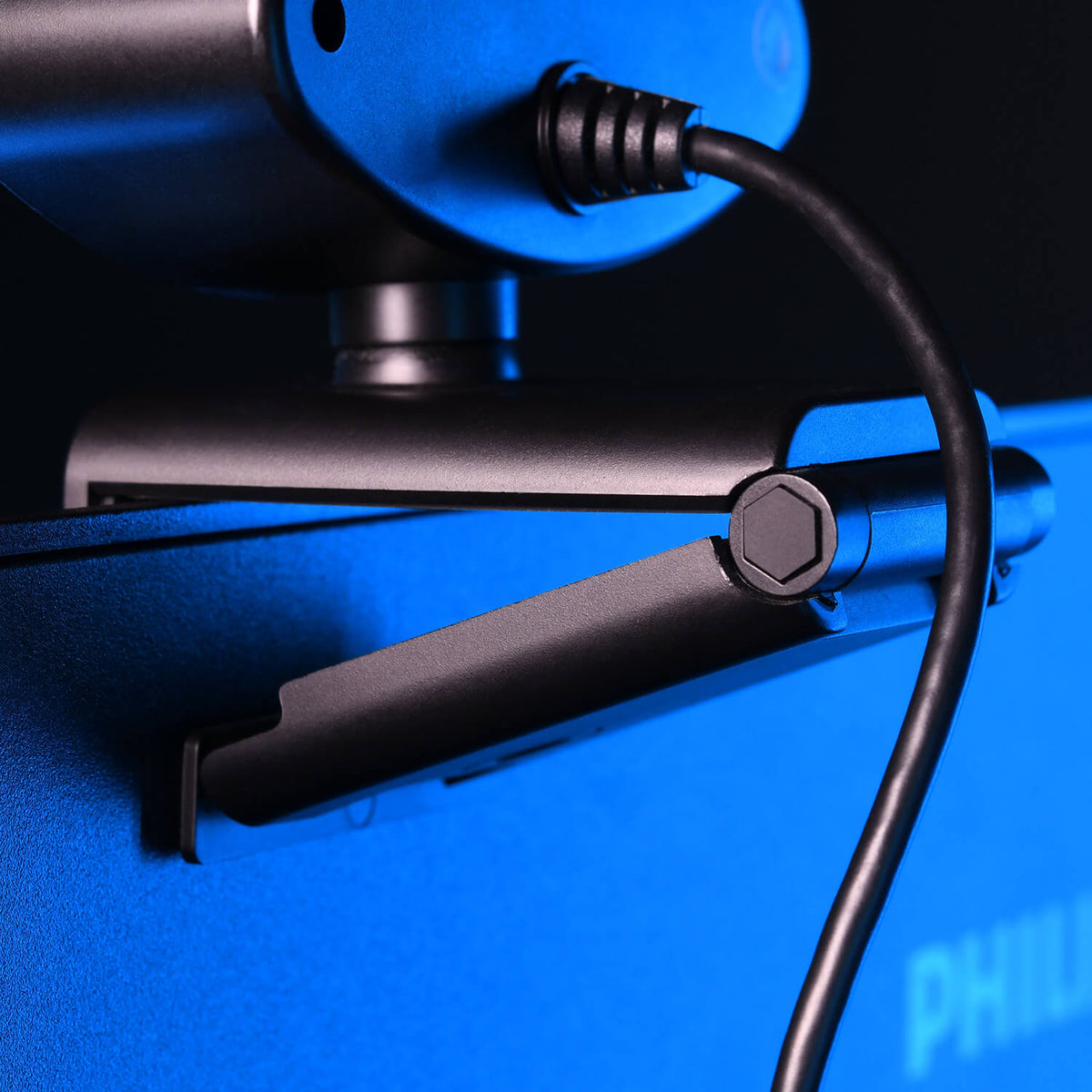 Close-up of a webcam clipped to a blue computer monitor with a visible cable.
