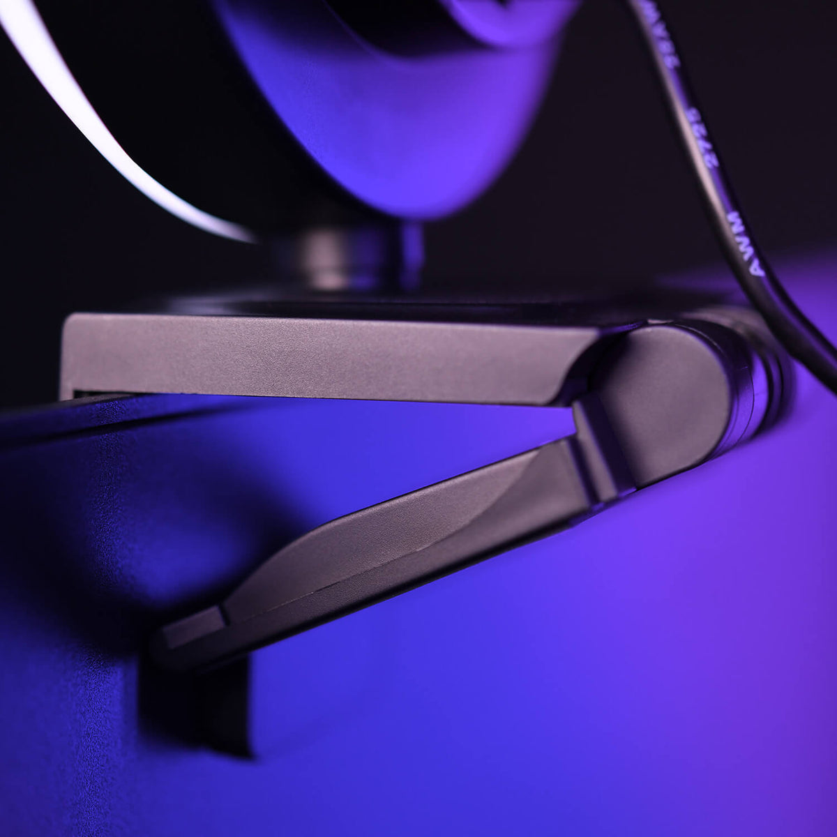 Close-up of a webcam clipped to a monitor, lit with purple and blue lighting.