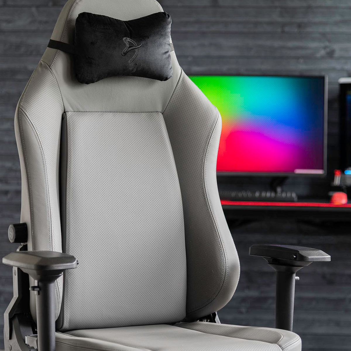 Arozzi Primo Full Premium Leather chair faces a desk and colorful monitor, black headrest shown.