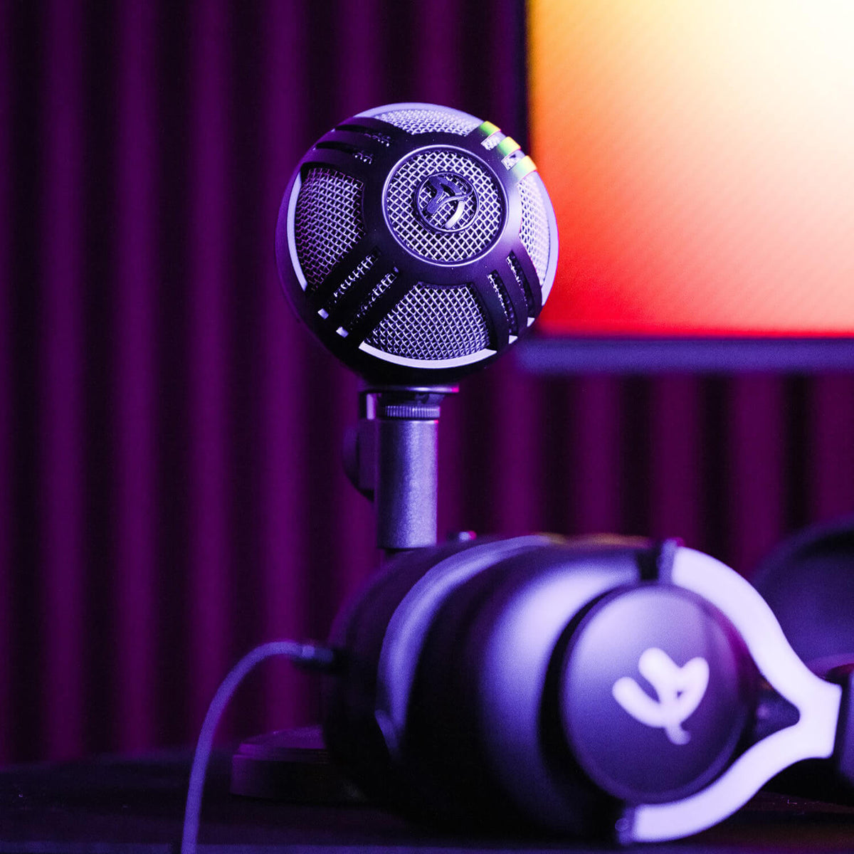 Arozzi Europe Sfera Microphone and headphones on desk with purple lighting in background.