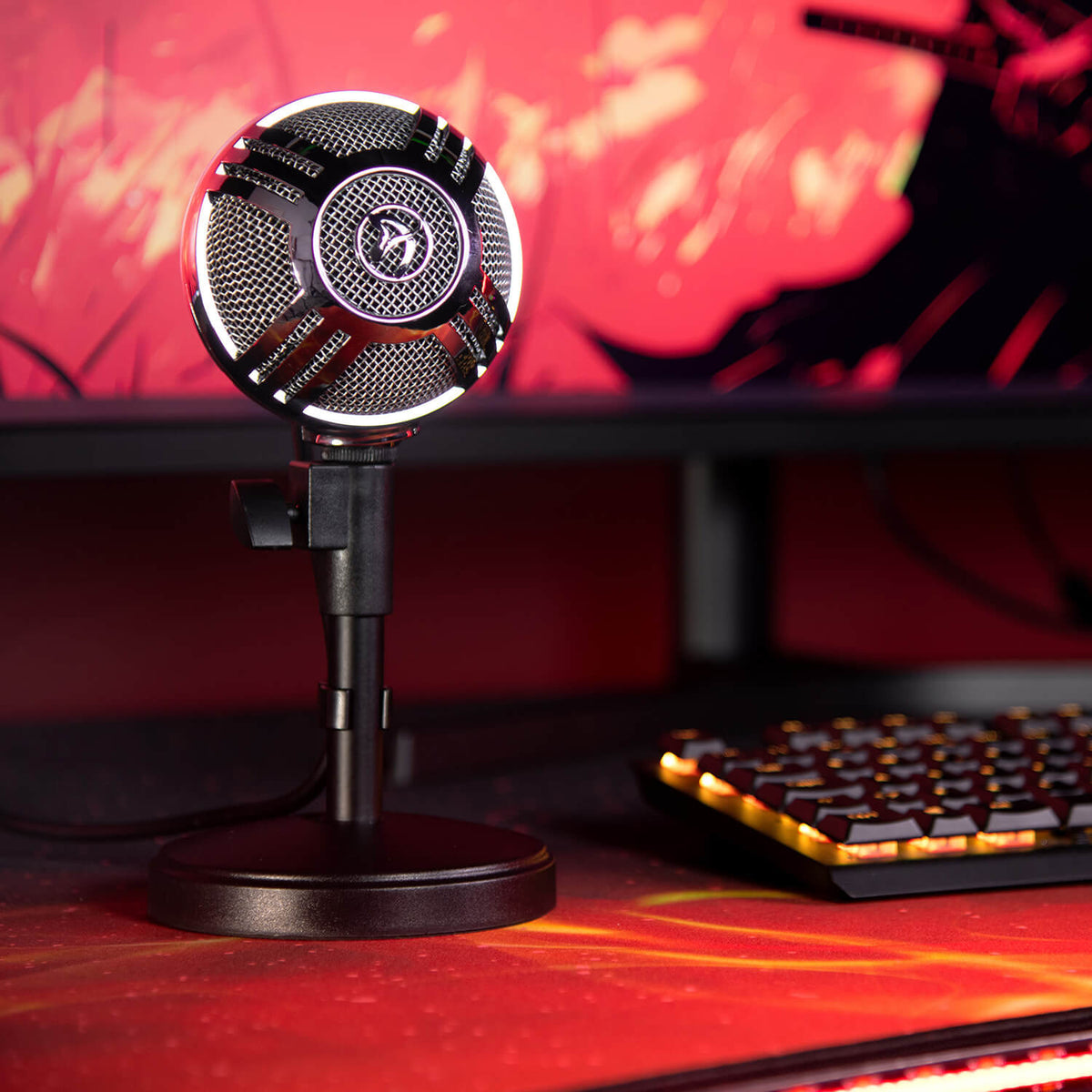Arozzi Europe Sfera Microphone on a stand is next to a keyboard, with a red monitor behind.