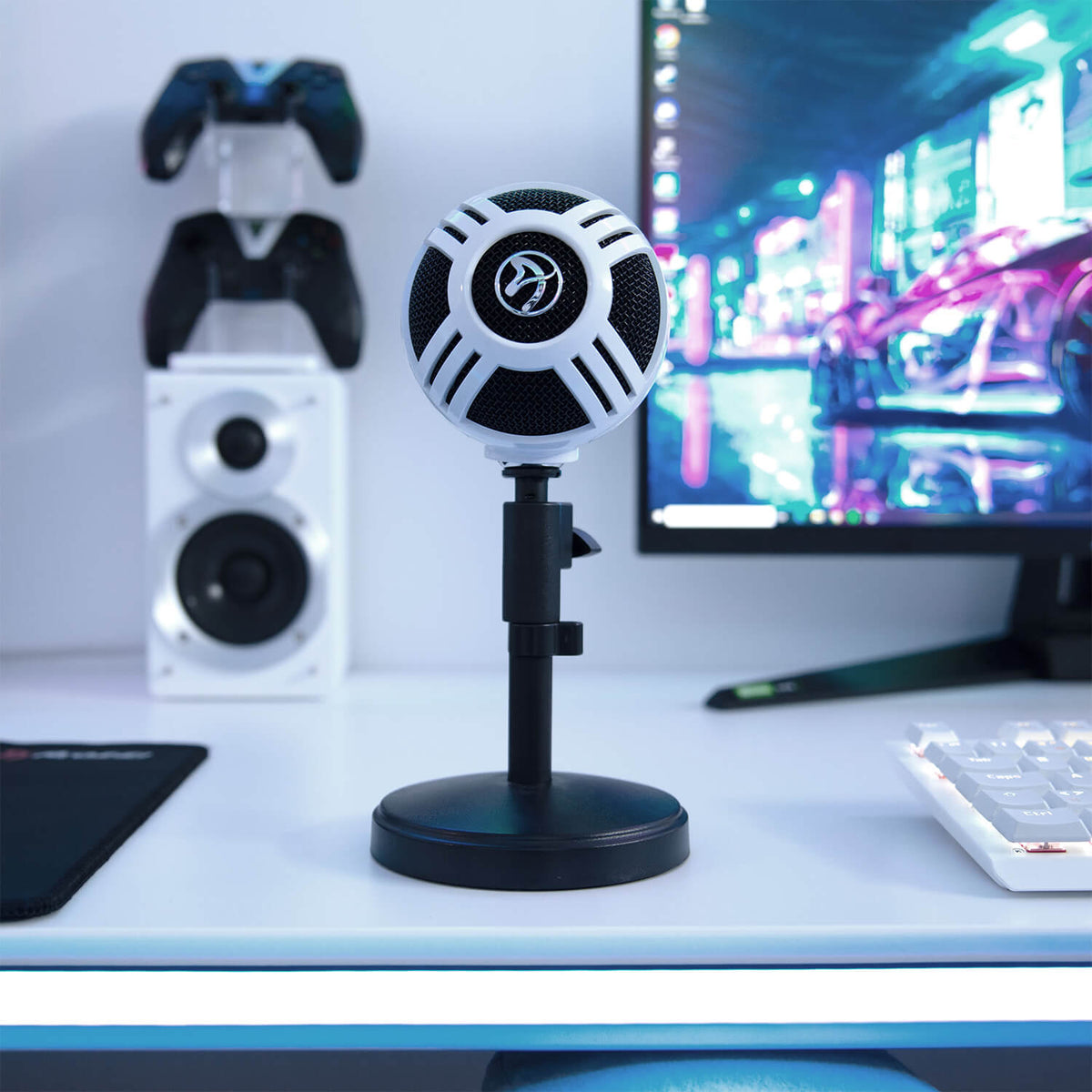 Arozzi Europe Sfera Microphone on a desk with monitor, keyboard, and game controllers nearby.