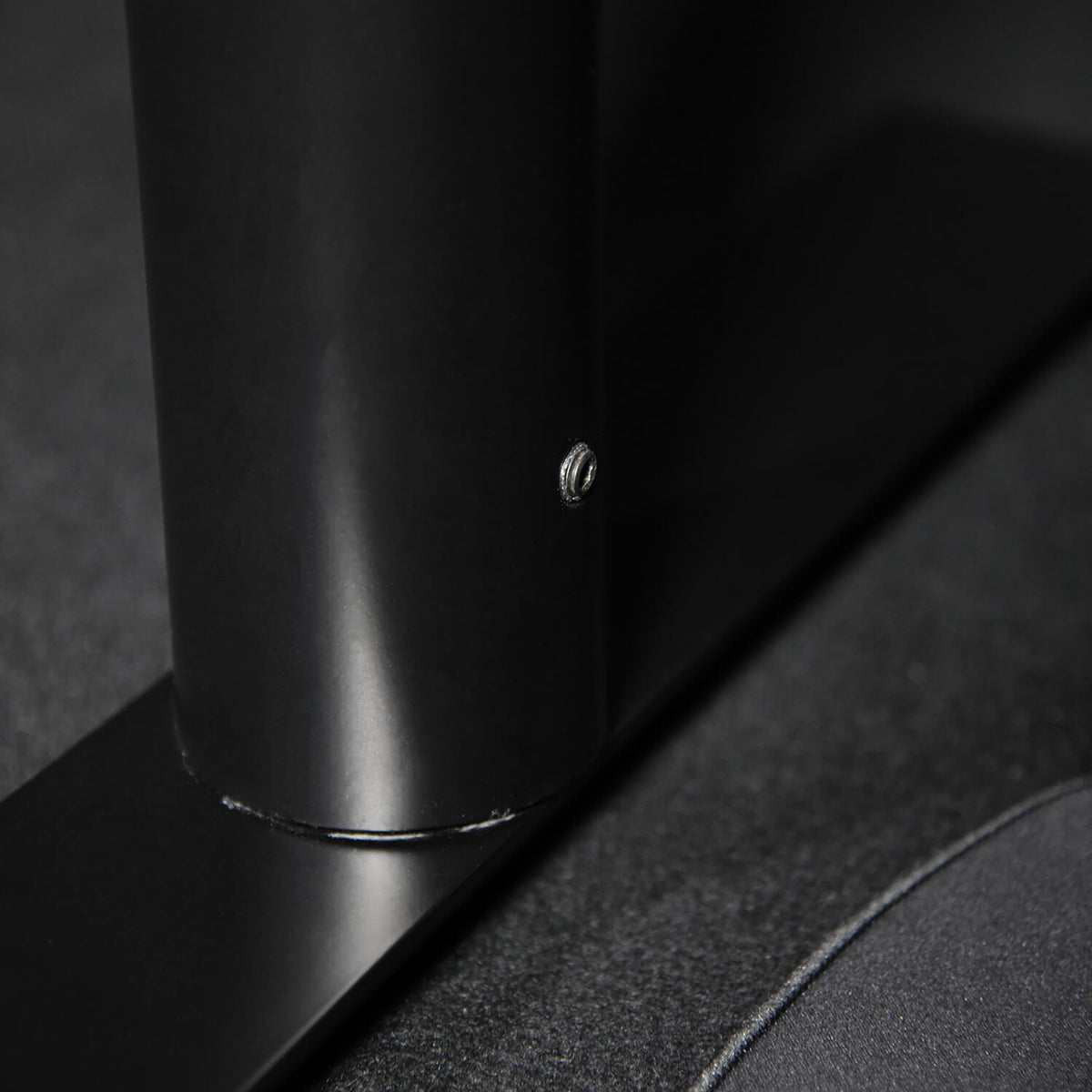 Close-up of a black metal pole attached to a flat base with a visible screw.