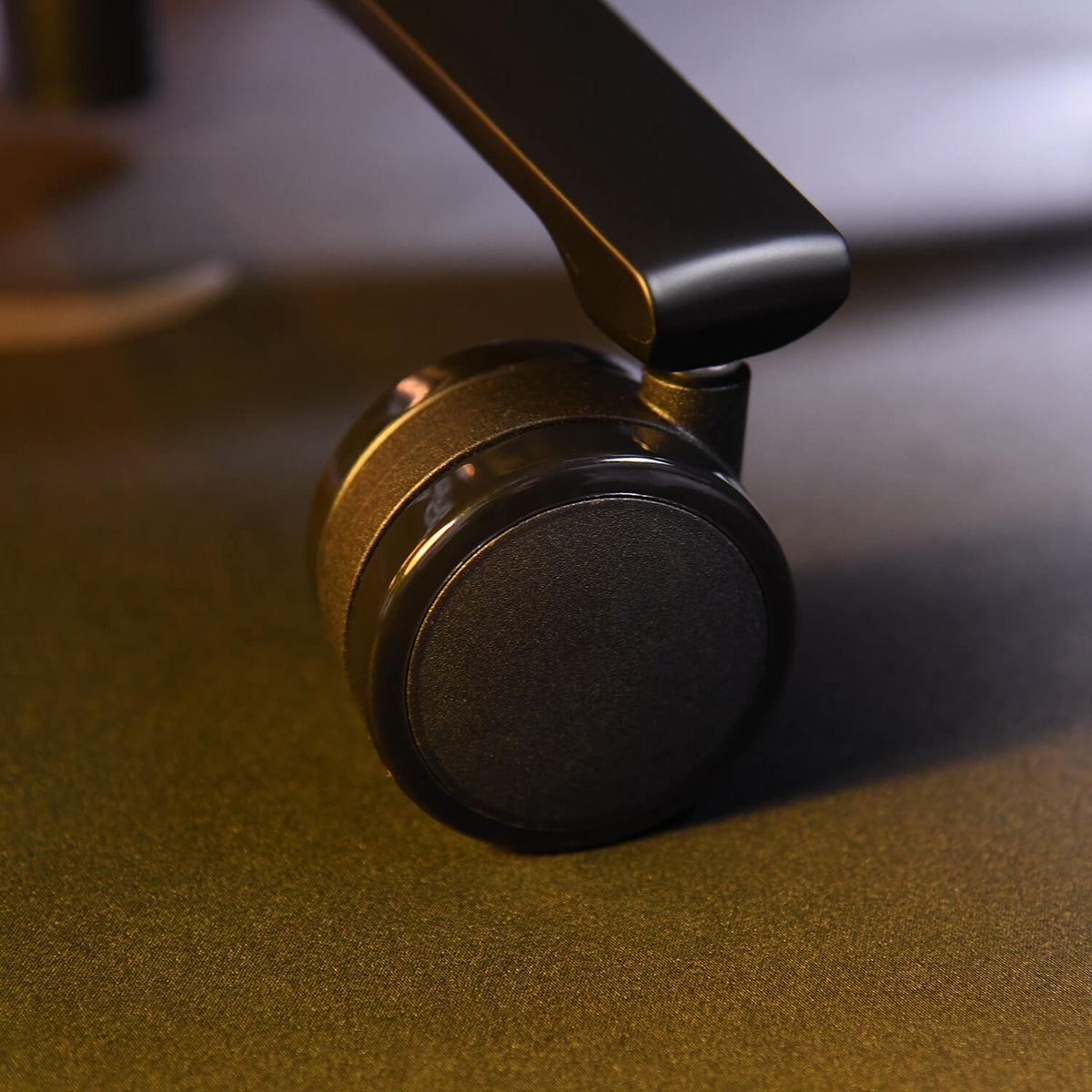 Close-up of a black office chair caster wheel on a smooth surface.