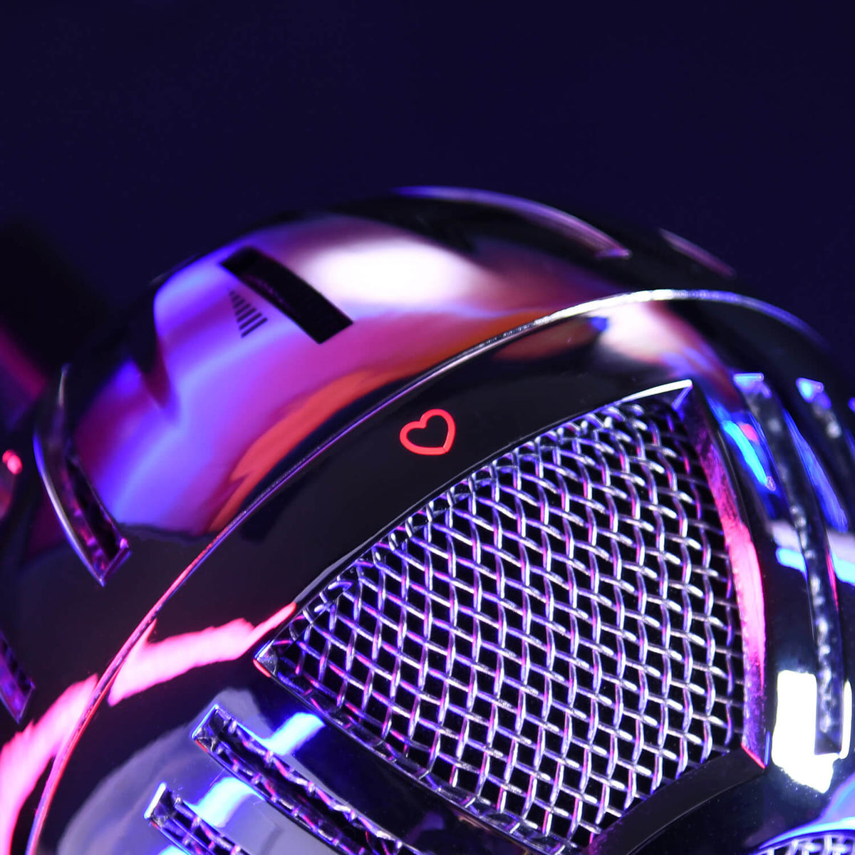 Close-up of a shiny microphone with a small red heart symbol, lit by pink and blue lights.