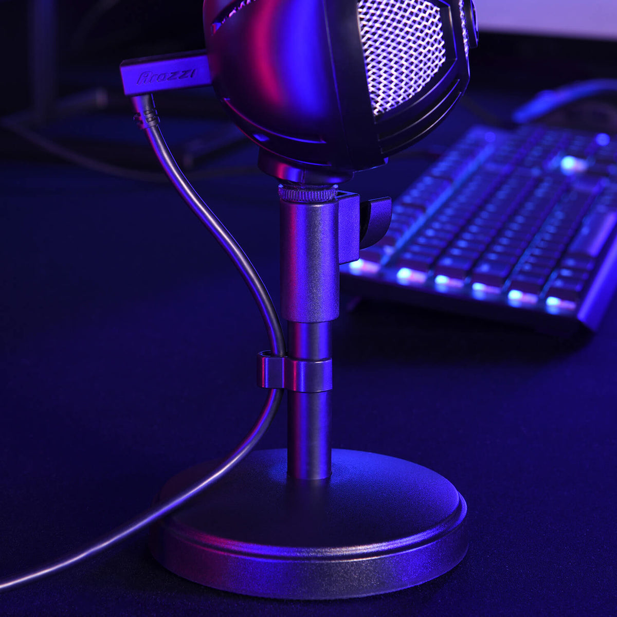 A microphone on a stand next to a backlit keyboard, both lit with purple and blue lights.