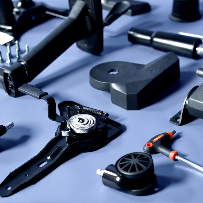 Various black metal and plastic mechanical parts and tools on a blue surface.