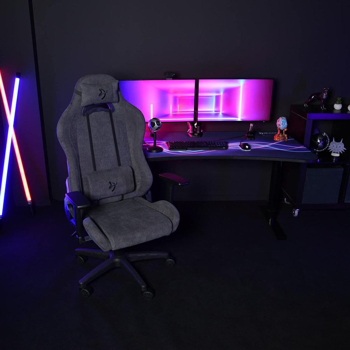 Arozzi Europe Torretta Soft Fabric chair in front of a dual-monitor RGB desk, dark room.