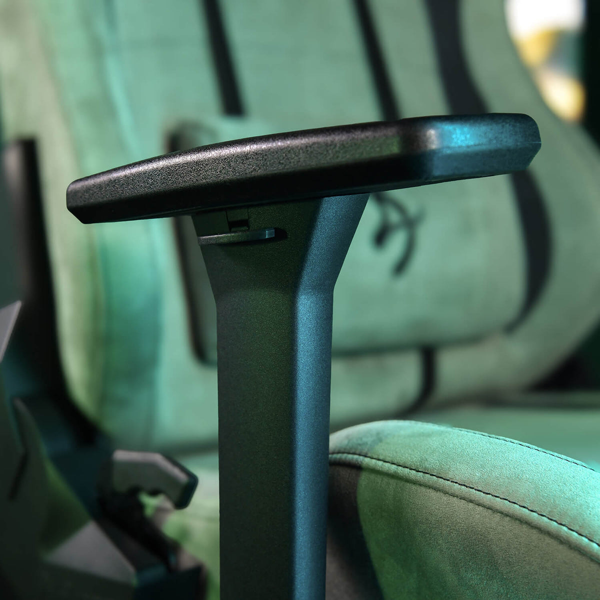 Close-up of a black armrest attached to a green padded chair or seat.
