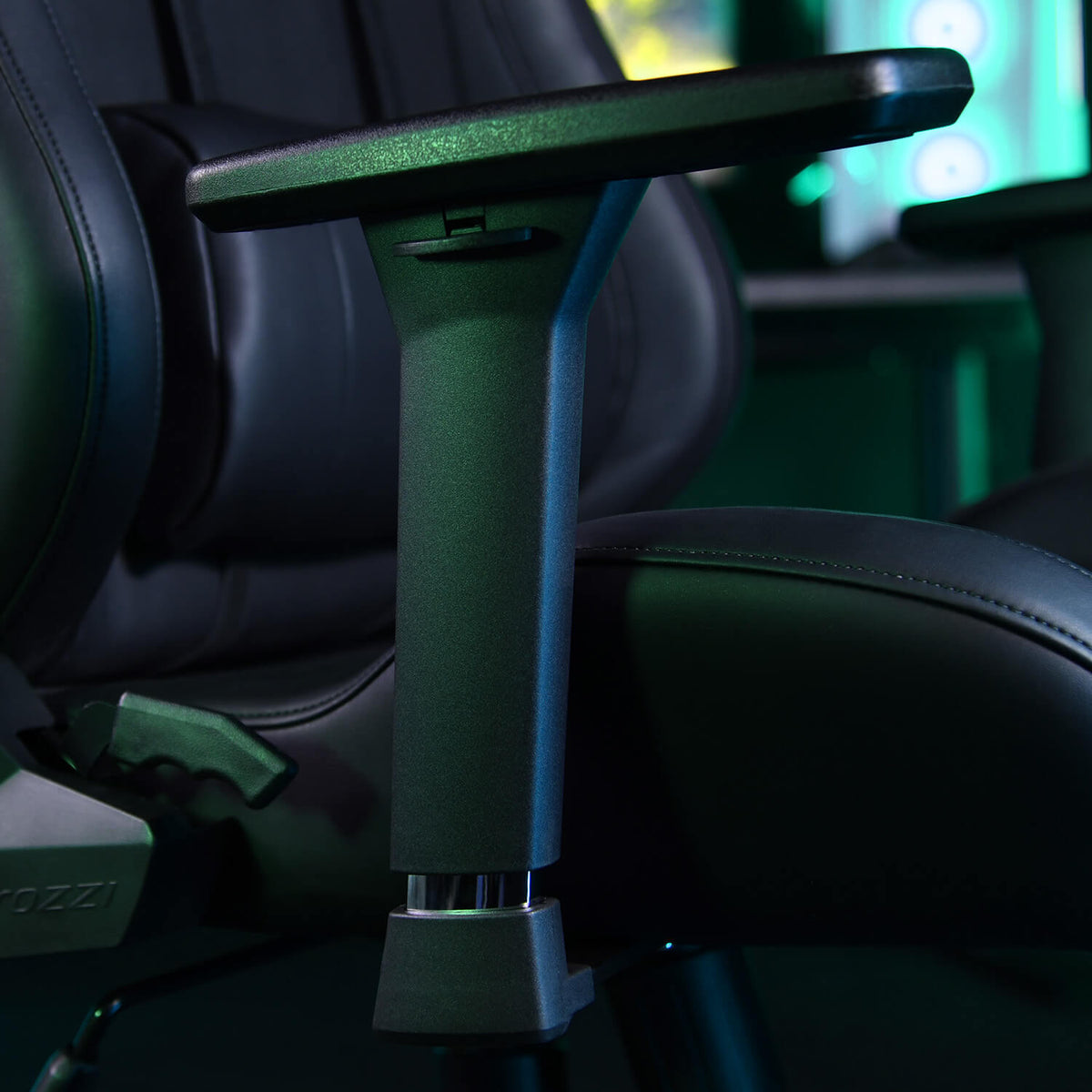 Close-up of a black gaming chair armrest with controls, under blue-green lighting.