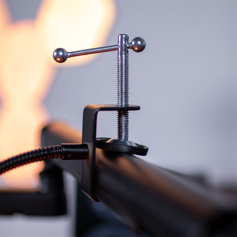 Close-up of a metal clamp attached to a black tube with a blurred light in the background.