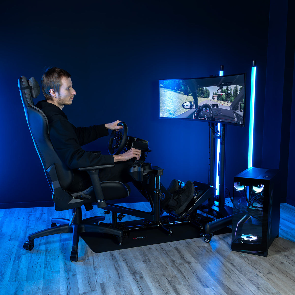 User plays on Arozzi Europe Velocità Racing Simulator Stand in a blue-lit room with wheel attached.