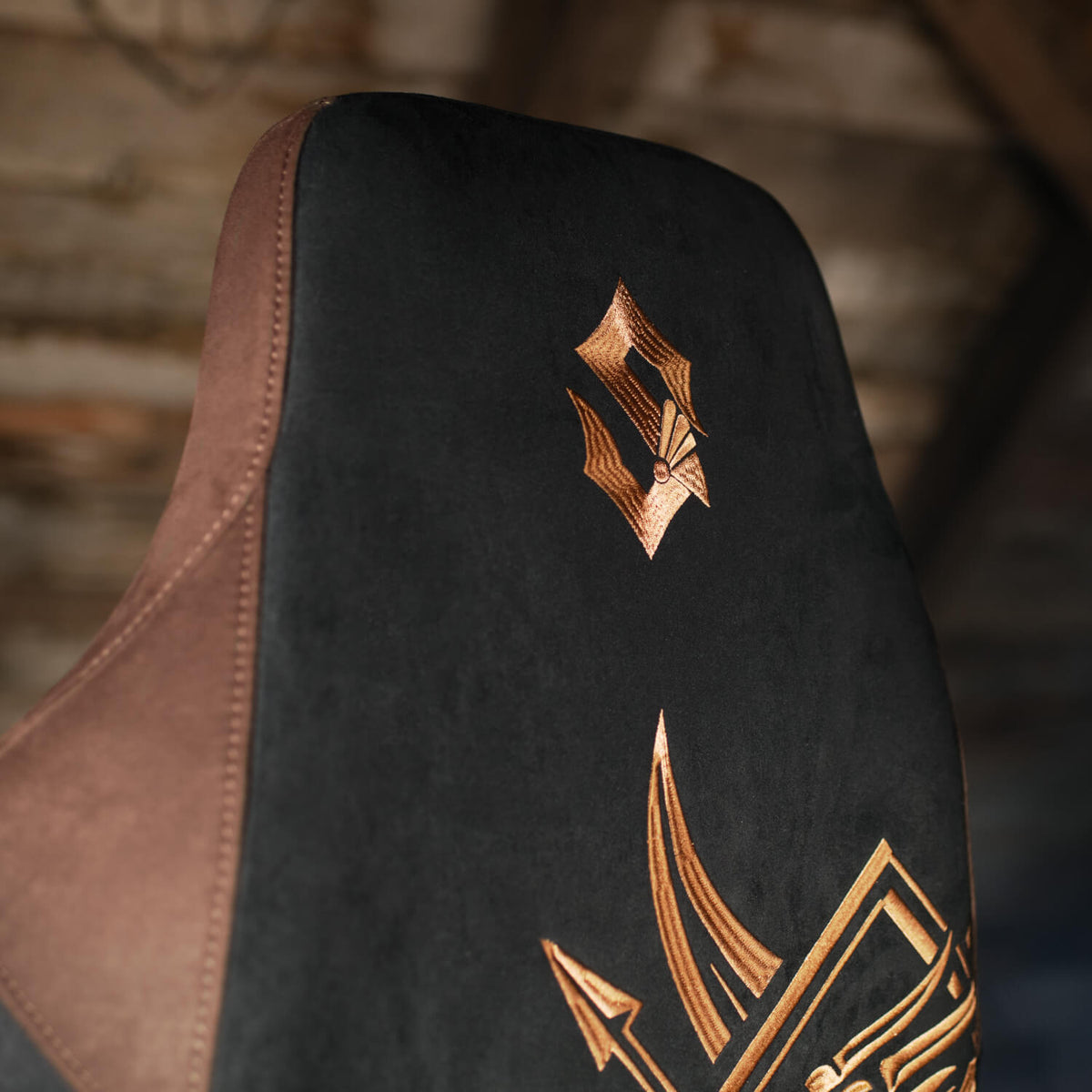Arozzi Vernazza Supersoft Sabaton Legends chair in black/brown with gold, on wood background.