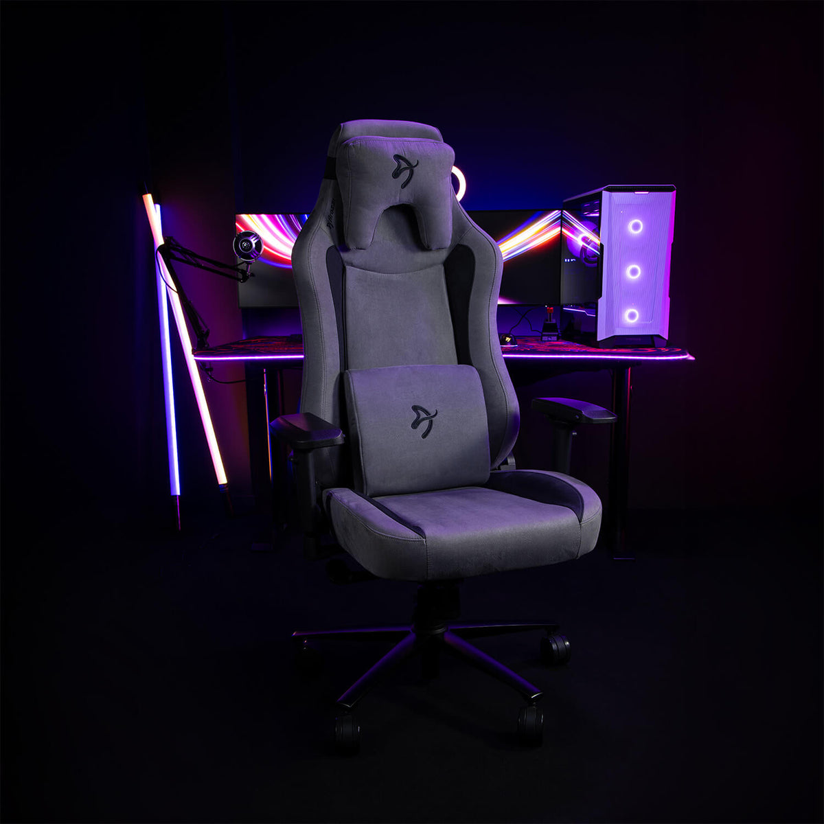 Arozzi Europe Vernazza Supersoft chair in front of a neon-lit PC setup in a dark room.