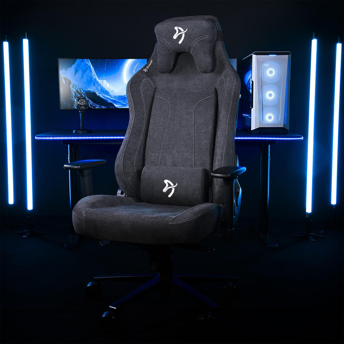 Arozzi Europe’s Vernazza XL Soft Fabric gaming chair in gray faces a PC and blue LED-lit space.