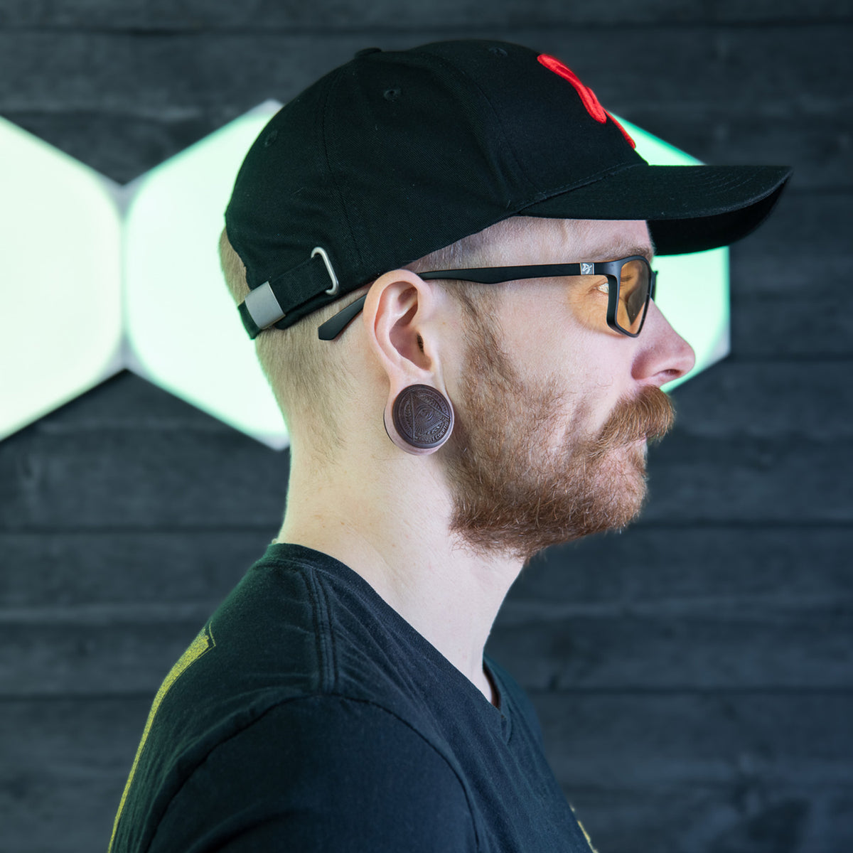 Man in profile wearing Arozzi Europe Visione VX-200 blue light glasses, cap, & black shirt.