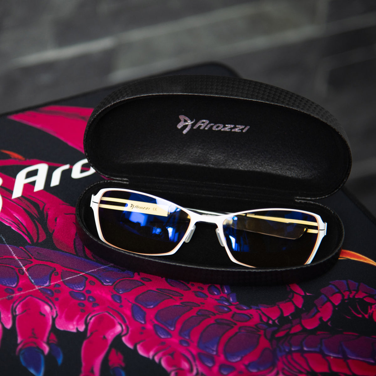 Arozzi Europe Visione VX-500 blue light glasses in black case on dragon desk mat for computers.