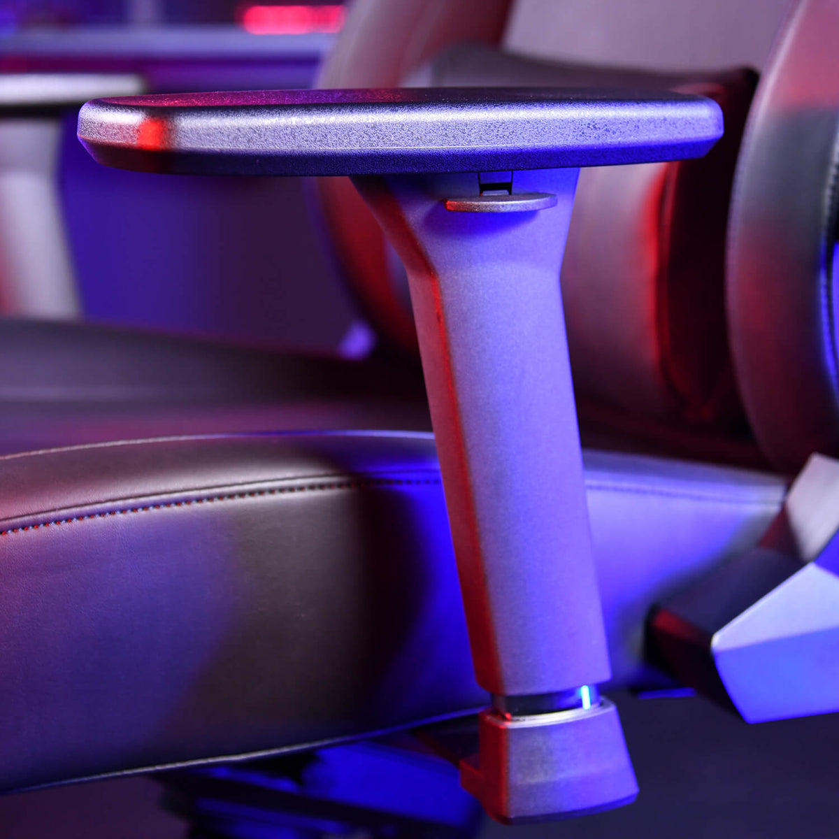 Close-up of an adjustable chair armrest with blue and red lighting.