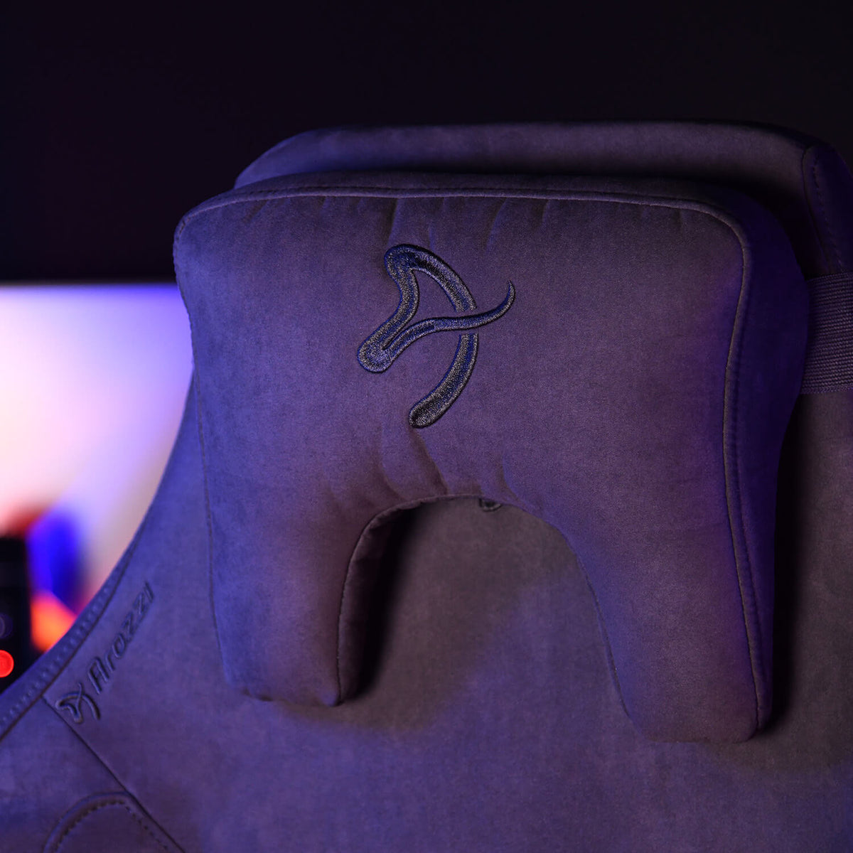Close-up of a dark gaming chair with a memory foam headrest pillow attached.