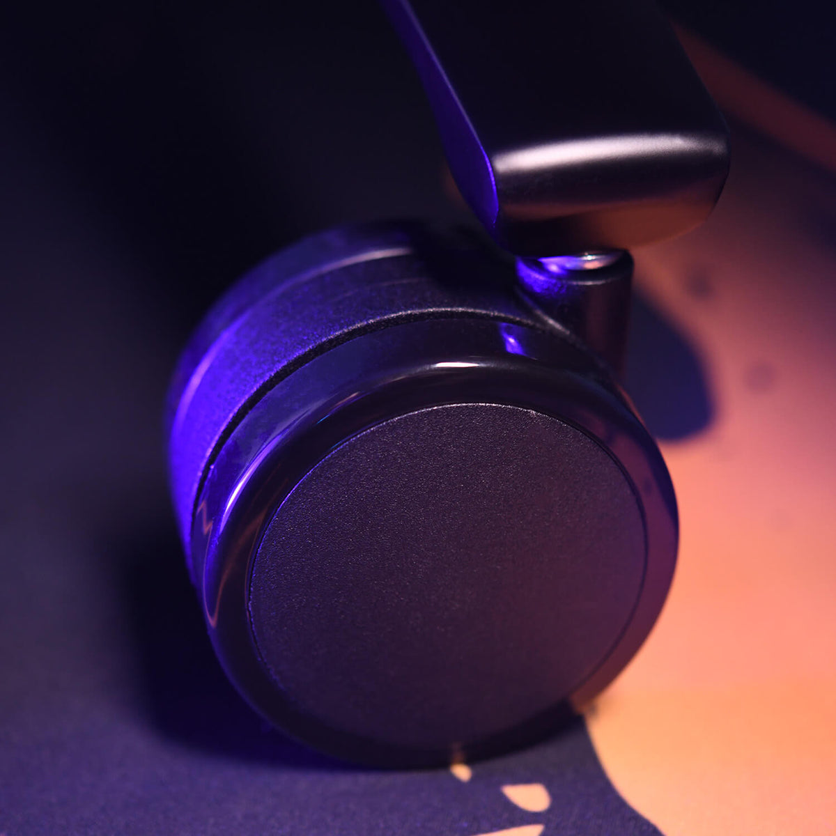 Close-up of a black chair caster wheel with purple lighting on a dark surface.