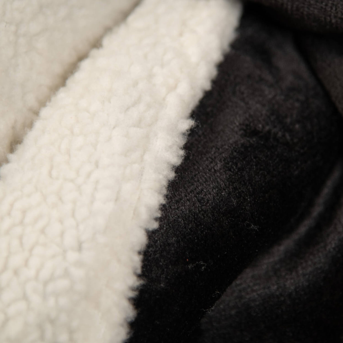 Close-up of white fleece fabric next to a black textured fabric.