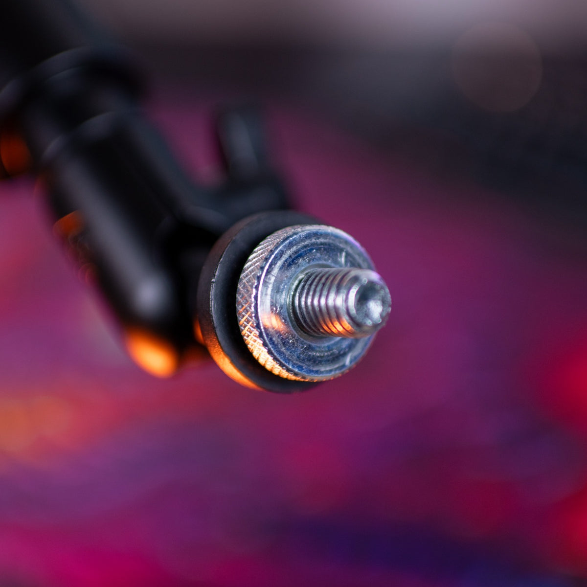 Close-up of a metal bolt with a colorful blurred background.