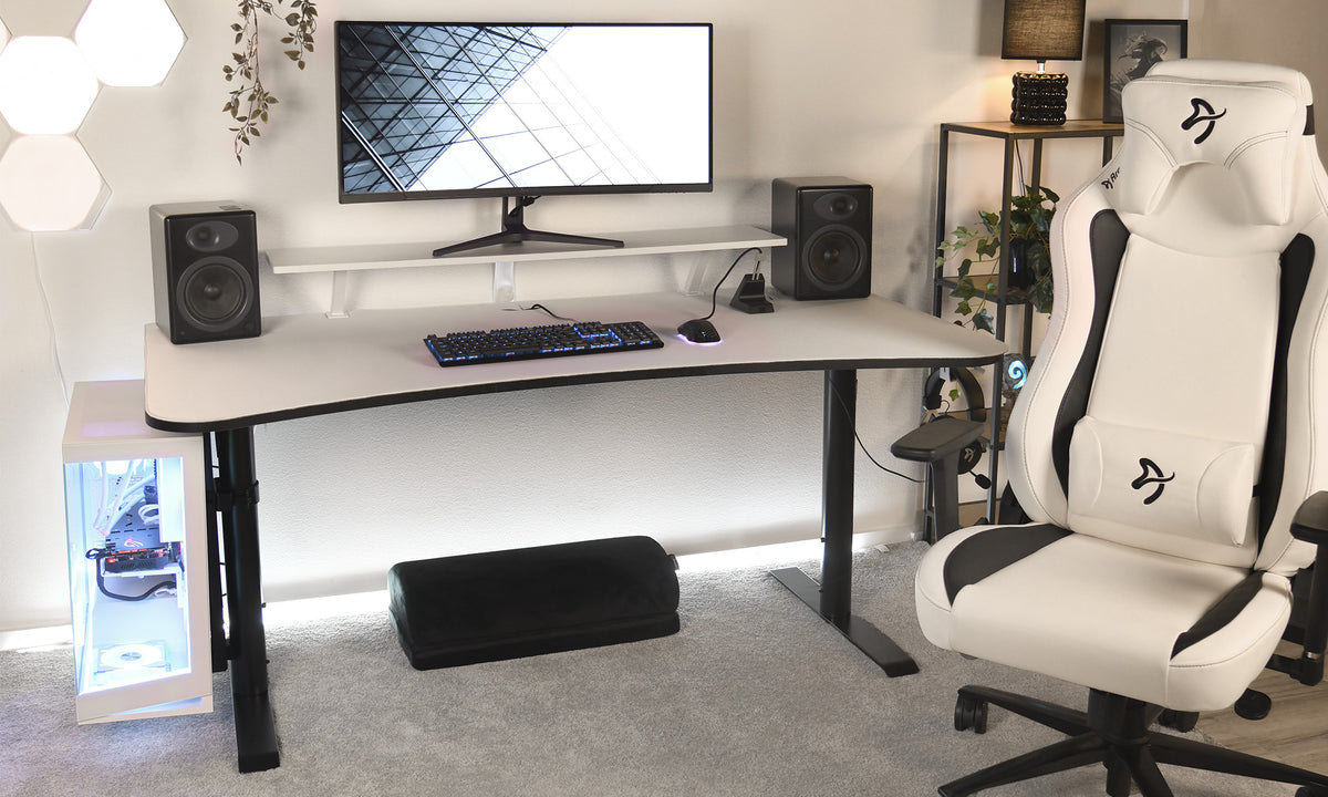 Modern gaming setup with a monitor, speakers, keyboard, and white gaming chair.