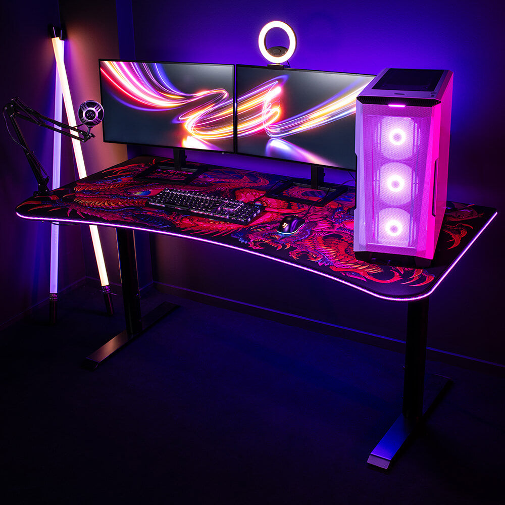 Dual monitors, RGB-lit PC, and neon lights on a desk with a vibrant dragon design.