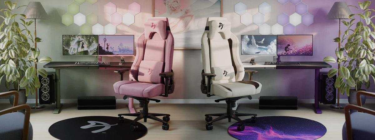 Two gaming chairs in pastel colors sit in front of dual-monitor gaming desk setups.