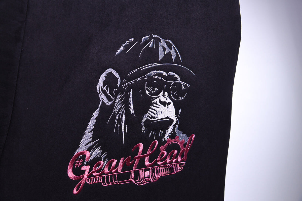 Embroidered chimp in a helmet and glasses, with GearHead text on a black fabric background.